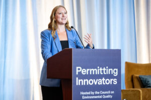 Emily Domenech gestures while speaking at the lectern.