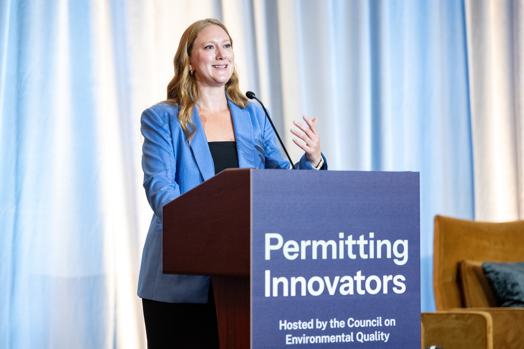 Emily Domenech gestures while speaking at the lectern.