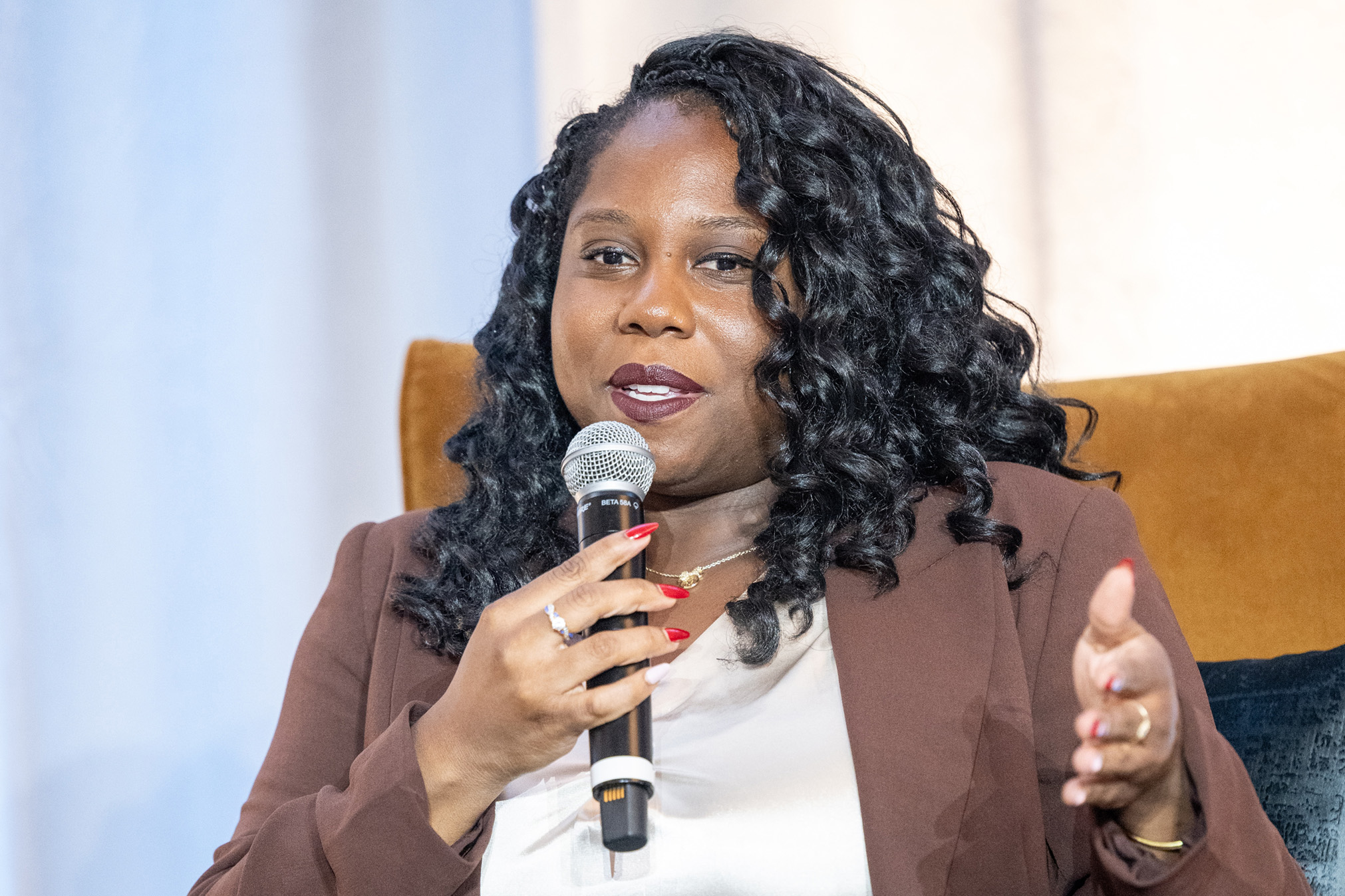 Monica Taylor speaks into a microphone on stage.