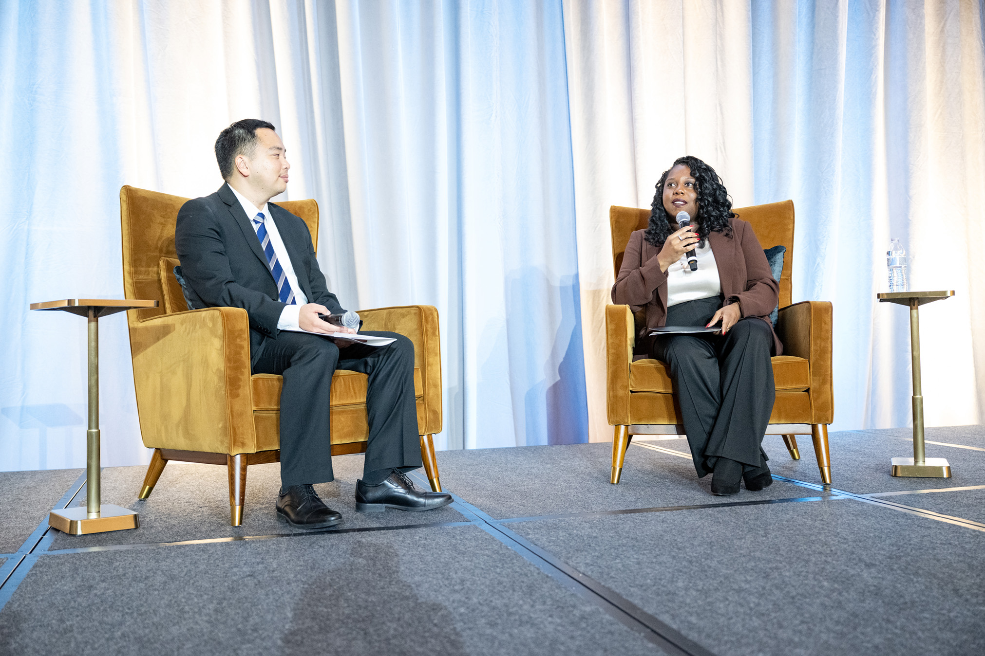 David Yi and Monica Taylor sit side by side on stage.