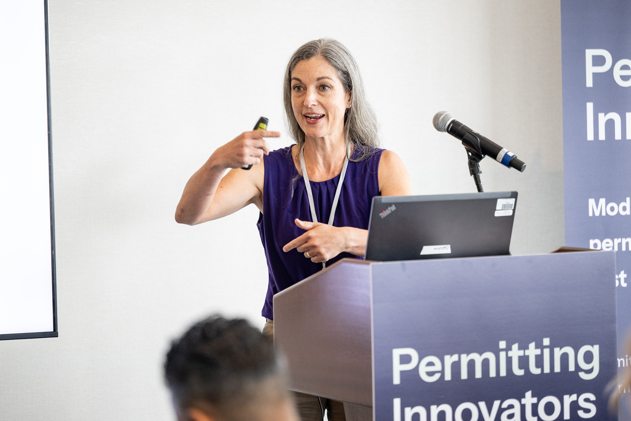 Elizabeth Ayer gestures toward the audience while presenting at the lectern.
